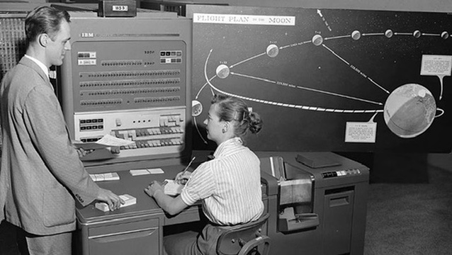 A vintage mission-planning control room with two people at a console and orbital diagrams on the wall.